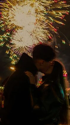 a man and woman kissing in front of fireworks