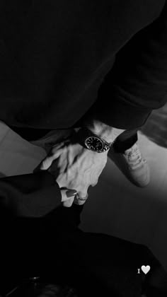 black and white photograph of two people holding hands with one person wearing a watch on their wrist