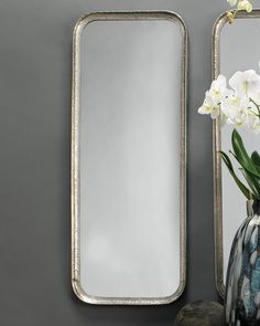 a vase with white flowers sitting next to a mirror