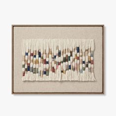 an art piece with many different colors and shapes on the fabric, hanging in a wooden frame