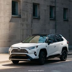 a white toyota rav parked in front of a building