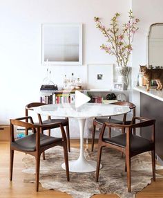 a cat sitting on top of a table next to two chairs