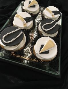 cupcakes decorated with black and white icing are on a glass platter