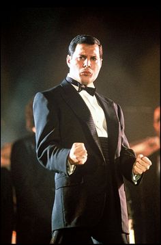 a man in a tuxedo and bow tie pointing his finger at the camera