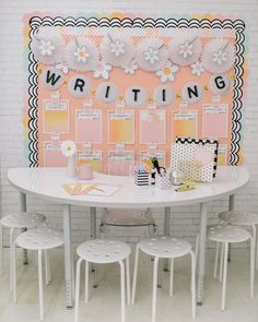 a white table with four chairs and a writing board on the wall in front of it