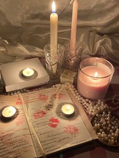 an open book with candles on it and other items around it, including two votives