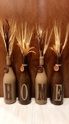 three vases with wheat stalks and the word home painted on them are lined up against a wall