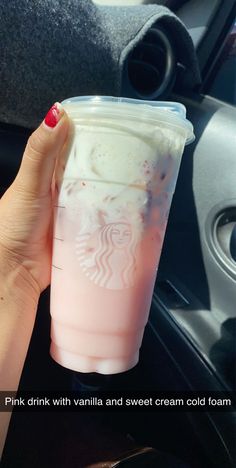 a woman holding up a pink drink with vanilla and sweet cream cold foam in her hand