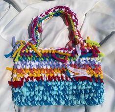 a multicolored purse sitting on top of a white sheet