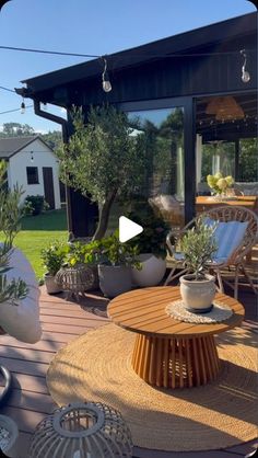 an outdoor living area with potted plants and wicker furniture in front of the house