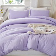 a bed with purple comforter and pillows