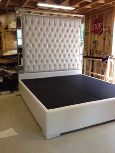 a white bed frame in a room with wood flooring and exposed lighting above it