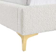 a bed with white sheets and gold legs