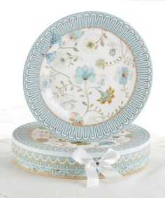 two blue and white plates sitting on top of each other next to a box with a bow