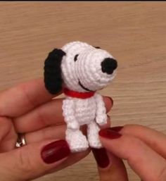 a hand holding a small crocheted dog on it's fingernails