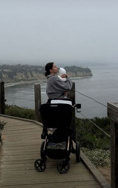 a woman holding a baby in her arms while sitting on top of a wooden walkway