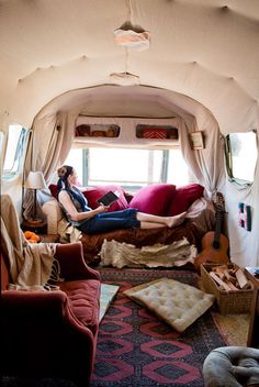 a woman laying on top of a bed in a room with lots of furniture and pillows