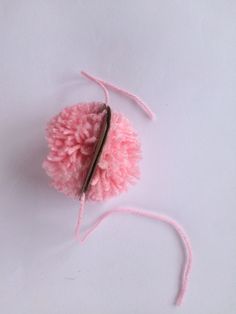 a pink pom - pom on a white surface with a string attached to it