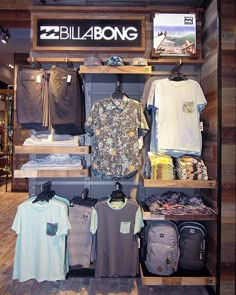 a display case filled with shirts and backpacks in front of a sign that says billabong