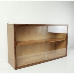 an empty wooden shelf with glass doors on the top and bottom shelves, against a white wall