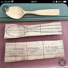 three wooden spoons and two pieces of wood with writing on them are sitting next to each other