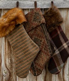 three mittens hanging on a wooden fence with fur lined around the top and bottom