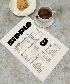 a table topped with a cup of coffee next to a cookie