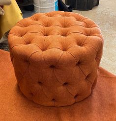 an orange ottoman sitting on top of a table next to other furniture and decor items