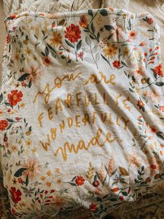 a blanket with writing on it sitting on top of a bed next to a pillow