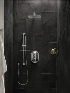 a bathroom with black tiles and a shower head