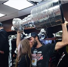 a man and woman kissing each other while holding up the stanley cup