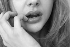 a black and white photo of a woman talking on a cell phone with her hand to her ear