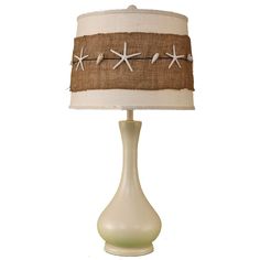 a table lamp with a starfish design on the bottom and a beige shade over it