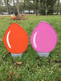 two orange and pink frisbees sitting in the grass near eachother