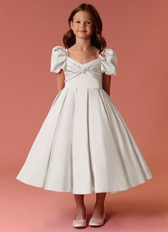 This tea length dress features puff sleeves, a detachable bow back, a hand sewn rhinestone pendant, a box pleated skirt, and pockets. Sunday Best Pageant Dresses Toddler, Classy Kids Dresses, Flower Girl Dress Ideas, Satin Flower Girl Dresses, Kids Bridesmaid Dress, Kids White Dress, Satin Flower Girl Dress, Stretch Satin Dress, Aesthetic Galaxy