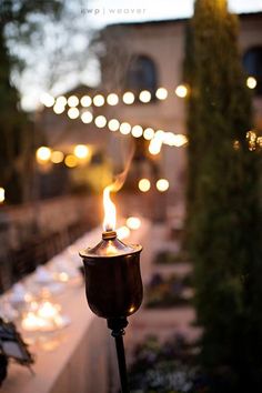 a lit candle sitting on top of a table next to a white cloth covered table