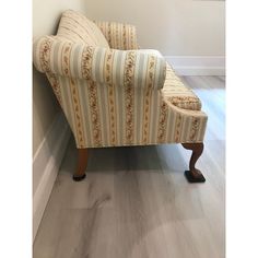 a striped chair sitting on top of a hard wood floor next to a white wall