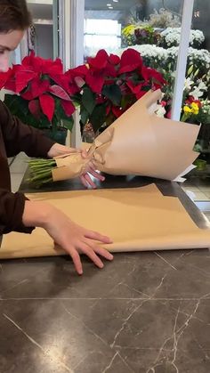 a woman is making flowers out of wrapping paper