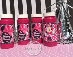 three pink bottles with minnie mouse designs on them sitting on a polka dot tablecloth