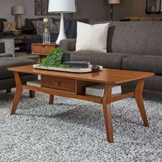 a living room filled with furniture and a lamp on top of a wooden coffee table