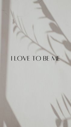 i love to be me written in black on a white wall with shadow from the plant