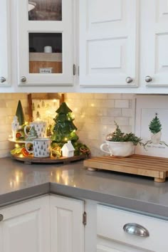 a kitchen with white cabinets and christmas decorations on the counter top, along with a cutting board