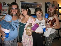 three women are posing for the camera with one holding a baby in her arms and another holding a stuffed animal