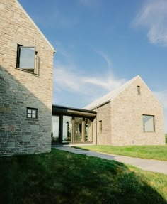 a brick house sitting on top of a lush green field next to a stone building