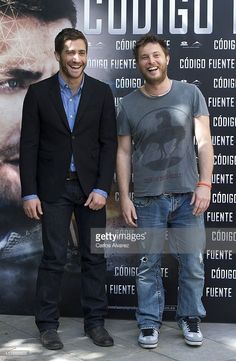 two men standing next to each other in front of a wall with a movie poster on it