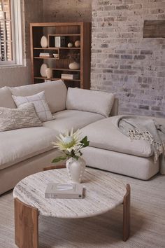 a living room with a couch, coffee table and bookshelf in the corner