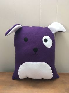 a purple dog pillow sitting on top of a wooden table