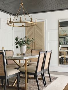 a dining room table with chairs and a potted plant