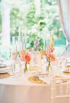 the table is set with wine glasses, flowers and place cards for guests to sit at