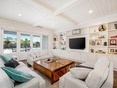 a living room filled with furniture and a flat screen tv mounted on a wall above a wooden coffee table